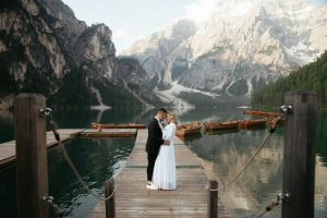 Bride and groom next to a lake in Italy with mountains